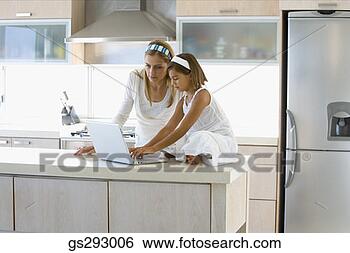 Stock Photo - mother and daughter 
using laptop in 
kitchen. fotosearch 
- search stock 
photos, pictures, 
images, and photo 
clipart