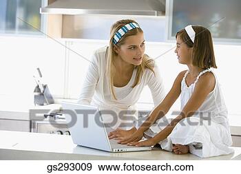 Stock Photograph - mother and daughter 
using laptop in 
kitchen. fotosearch 
- search stock 
photos, pictures, 
images, and photo 
clipart
