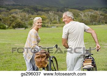 Picture - couple walking 
bikes in field. 
fotosearch - search 
stock photos, 
pictures, images, 
and photo clipart