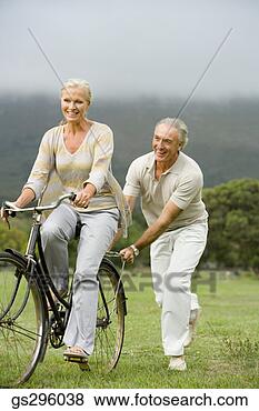 Stock Photo - man pushing woman 
on bike in field. 
fotosearch - search 
stock photos, 
pictures, images, 
and photo clipart