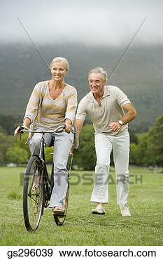 Stock Photograph - man pushing woman 
on bike in field. 
fotosearch - search 
stock photos, 
pictures, images, 
and photo clipart