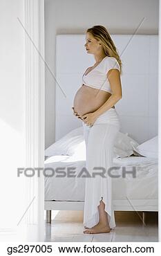 Stock Image - pregnant woman 
standing by bed. 
fotosearch - search 
stock photos, 
pictures, images, 
and photo clipart