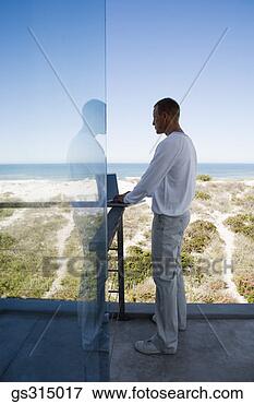 Picture - man standing on 
balcony with laptop. 
fotosearch - search 
stock photos, 
pictures, images, 
and photo clipart