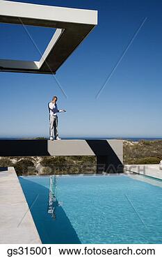 Stock Photography - man standing on 
ledge by pool. 
fotosearch - search 
stock photos, 
pictures, images, 
and photo clipart