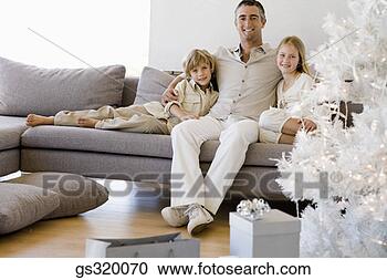 Stock Photography - family sitting 
by christmas tree. 
fotosearch - search 
stock photos, 
pictures, images, 
and photo clipart