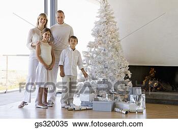Stock Image - family standing 
by christmas tree. 
fotosearch - search 
stock photos, 
pictures, images, 
and photo clipart