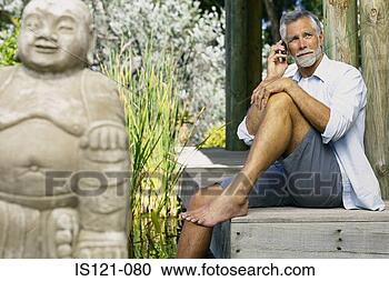 Stock Photography - man beside pool 
and buddha with 
cellphone. fotosearch 
- search stock 
photos, pictures, 
images, and photo 
clipart