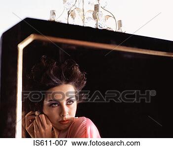 Picture - young woman adjusting 
earring in mirror. 
fotosearch - search 
stock photos, 
pictures, images, 
and photo clipart
