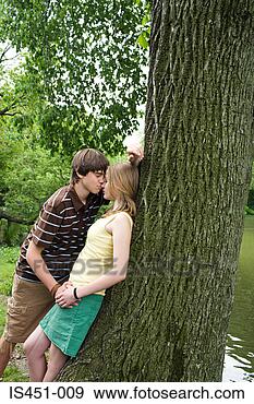 Arquivo Fotográficos - adolescente,  
par,  beijando, 
 árvore. fotosearch 
- busca de fotos, 
imagens e clipart