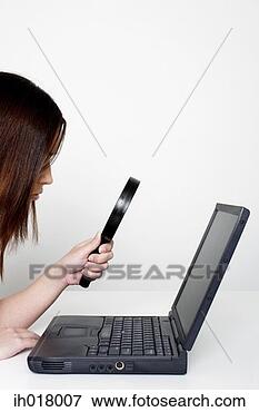 Picture - woman using magnifying 
glass to look 
at the words in 
the laptop. fotosearch 
- search stock 
photos, pictures, 
images, and photo 
clipart