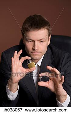 Picture - businessman looking 
at the lock and 
key in his hands. 
fotosearch - search 
stock photos, 
pictures, images, 
and photo clipart