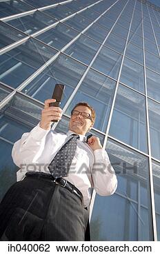 Stock Photo - businessman smiling 
while text messaging 
on the mobile 
phone. fotosearch 
- search stock 
photos, pictures, 
images, and photo 
clipart