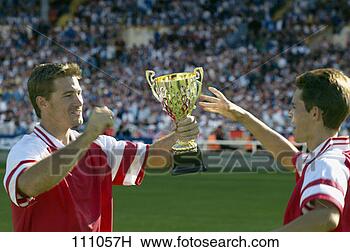 Stock Photo - two male soccer 
players reach 
for the trophy 
after a soccer 
match. fotosearch 
- search stock 
photos, pictures, 
images, and photo 
clipart
