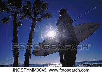 Stock Photo - silhouette of 
a man holding 
a surfboard standing 
on a beach. fotosearch 
- search stock 
photos, pictures, 
images, and photo 
clipart