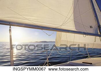 Picture - view of the sun 
setting through 
the sails of a 
sailboat. fotosearch 
- search stock 
photos, pictures, 
images, and photo 
clipart