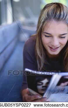Picture - close-up of a 
young woman lying 
and reading a 
magazine. fotosearch 
- search stock 
photos, pictures, 
images, and photo 
clipart