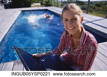 Stock Photography - high angle view 
of a young woman 
holding a laptop 
at a poolside. 
fotosearch - search 
stock photos, 
pictures, images, 
and photo clipart