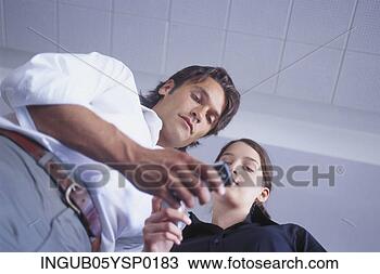 Stock Photo - low angle view 
of a young man 
and a young woman 
looking at a mobile. 
fotosearch - search 
stock photos, 
pictures, images, 
and photo clipart