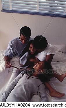 Stock Photo - parents on a bed 
with their two 
daughters. fotosearch 
- search stock 
photos, pictures, 
images, and photo 
clipart
