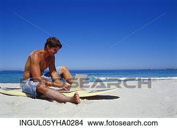 Stock Photo - young man sitting 
working on a laptop 
on the beach. 
fotosearch - search 
stock photos, 
pictures, images, 
and photo clipart