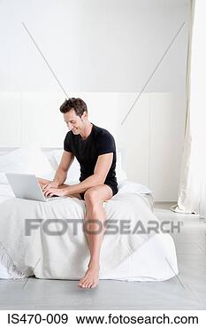 Stock Photograph - man using laptop 
on bed. fotosearch 
- search stock 
photos, pictures, 
images, and photo 
clipart
