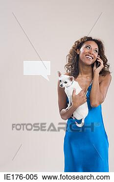 Stock Image - a woman holding 
a dog and using 
a cell phone. 
fotosearch - search 
stock photos, 
pictures, images, 
and photo clipart