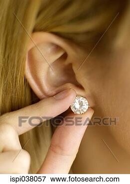Picture - putting on an 
earring. fotosearch 
- search stock 
photos, pictures, 
images, and photo 
clipart
