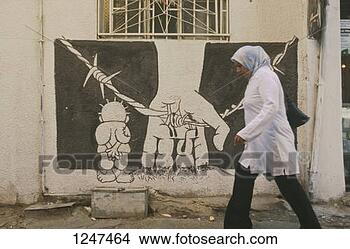 Stock Photo - a woman walking 
past graffiti 
in the shatila 
refugee camp, 
 beirut. fotosearch 
- search stock 
photos, pictures, 
images, and photo 
clipart