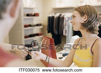 Stock Image - young woman making 
a purchase in 
a clothes shop. 
fotosearch - search 
stock photos, 
pictures, images, 
and photo clipart