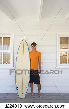 Stock Photograph - man with surfboard 
at beach house. 
fotosearch - search 
stock photos, 
pictures, images, 
and photo clipart