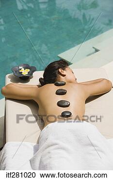 Stock Photography - woman lying by 
pool having stone 
spa treatment. 
fotosearch - search 
stock photos, 
pictures, images, 
and photo clipart