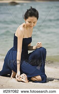 Stock Photo - woman on a beach 
with a seashell. 
fotosearch - search 
stock photos, 
pictures, images, 
and photo clipart