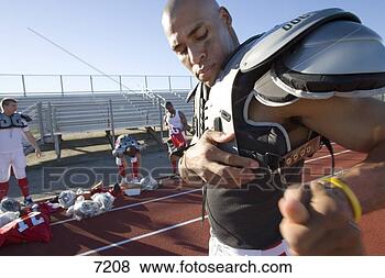 Stock Photo - american football 
player adjusting 
protective shoulder 
pad strap. fotosearch 
- search stock 
photos, pictures, 
images, and photo 
clipart