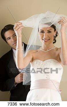 Stock Photo - groom standing 
behind bride at 
wedding,  bride 
removing veil. 
fotosearch - search 
stock photos, 
pictures, images, 
and photo clipart