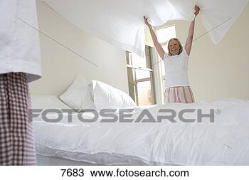 Stock Photo - mature couple 
making bed,  focus 
on woman holding 
bed sheet in. 
fotosearch - search 
stock photos, 
pictures, images, 
and photo clipart