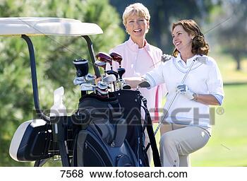 Stock Photo - two mature women 
standing beside 
parked golf buggy, 
 playing golf. 
fotosearch - search 
stock photos, 
pictures, images, 
and photo clipart