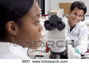 Picture - two medical lab 
technicians working 
with microscope 
in hospital lab. 
fotosearch - search 
stock photos, 
pictures, images, 
and photo clipart