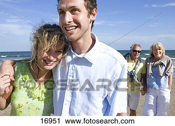 Stock Photography - young couple walking 
on beach, senior 
couple in background. 
fotosearch - search 
stock photos, 
pictures, images, 
and photo clipart