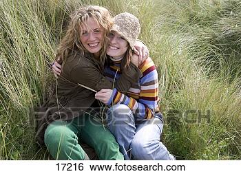 Stock Photo - young women hugging 
each other in 
grass. fotosearch 
- search stock 
photos, pictures, 
images, and photo 
clipart