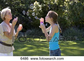 Stock Photo - senior woman and 
granddaughter 
(11-13) blowing 
soap bubbles into 
air. fotosearch 
- search stock 
photos, pictures, 
images, and photo 
clipart