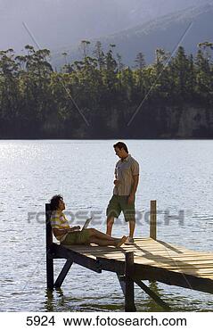 Stock Photo - two young men 
talking on lake 
jetty,  man leaning 
against wooden. 
fotosearch - search 
stock photos, 
pictures, images, 
and photo clipart