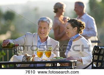 Stock Photography - mature couple 
dining at outdoor 
restaurant table, 
 man pouring glass. 
fotosearch - search 
stock photos, 
pictures, images, 
and photo clipart