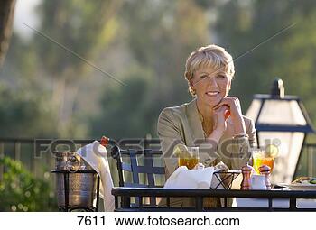 Stock Photography - mature woman dining 
at outdoor restaurant 
table,  smiling, 
 front. fotosearch 
- search stock 
photos, pictures, 
images, and photo 
clipart