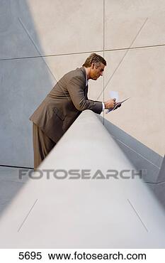Stock Image - mature businessman 
leaning on balcony 
railing,  reading 
document. fotosearch 
- search stock 
photos, pictures, 
images, and photo 
clipart