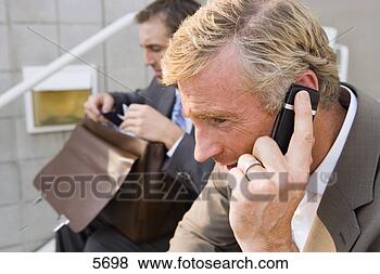 Stock Photo - two businessmen 
sitting on steps, 
 man looking in 
briefcase,  focus. 
fotosearch - search 
stock photos, 
pictures, images, 
and photo clipart