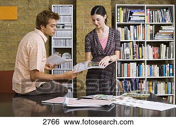 Stock Photo - young man and 
woman standing 
in office,  looking 
at designs in. 
fotosearch - search 
stock photos, 
pictures, images, 
and photo clipart