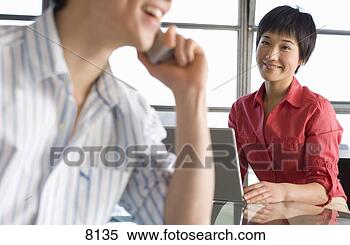 Stock Image - young woman with 
laptop,  smiling 
at man using telephone, 
 focus on. fotosearch 
- search stock 
photos, pictures, 
images, and photo 
clipart