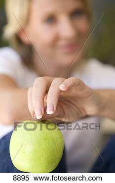 Stock Image - woman holding 
green apple,  
smiling,  portrait, 
 close-up (focus 
on. fotosearch 
- search stock 
photos, pictures, 
images, and photo 
clipart