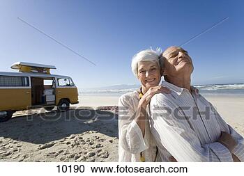 Stock Photography - senior woman embracing 
senior man from 
behind on beach 
by camper van. 
fotosearch - search 
stock photos, 
pictures, images, 
and photo clipart