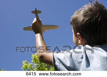 Stock Image - boy (8-10) playing 
with toy aeroplane 
in summer garden, 
 close-up. fotosearch 
- search stock 
photos, pictures, 
images, and photo 
clipart